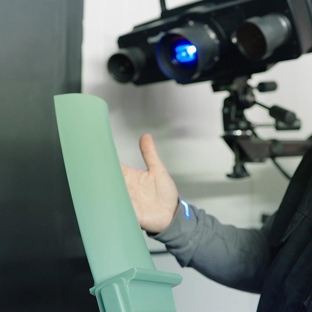 Un inspecteur examine un modèle de cire d'une pale, en se concentrant sur ses formes pour s'assurer de l'exactitude et de la précision du design.