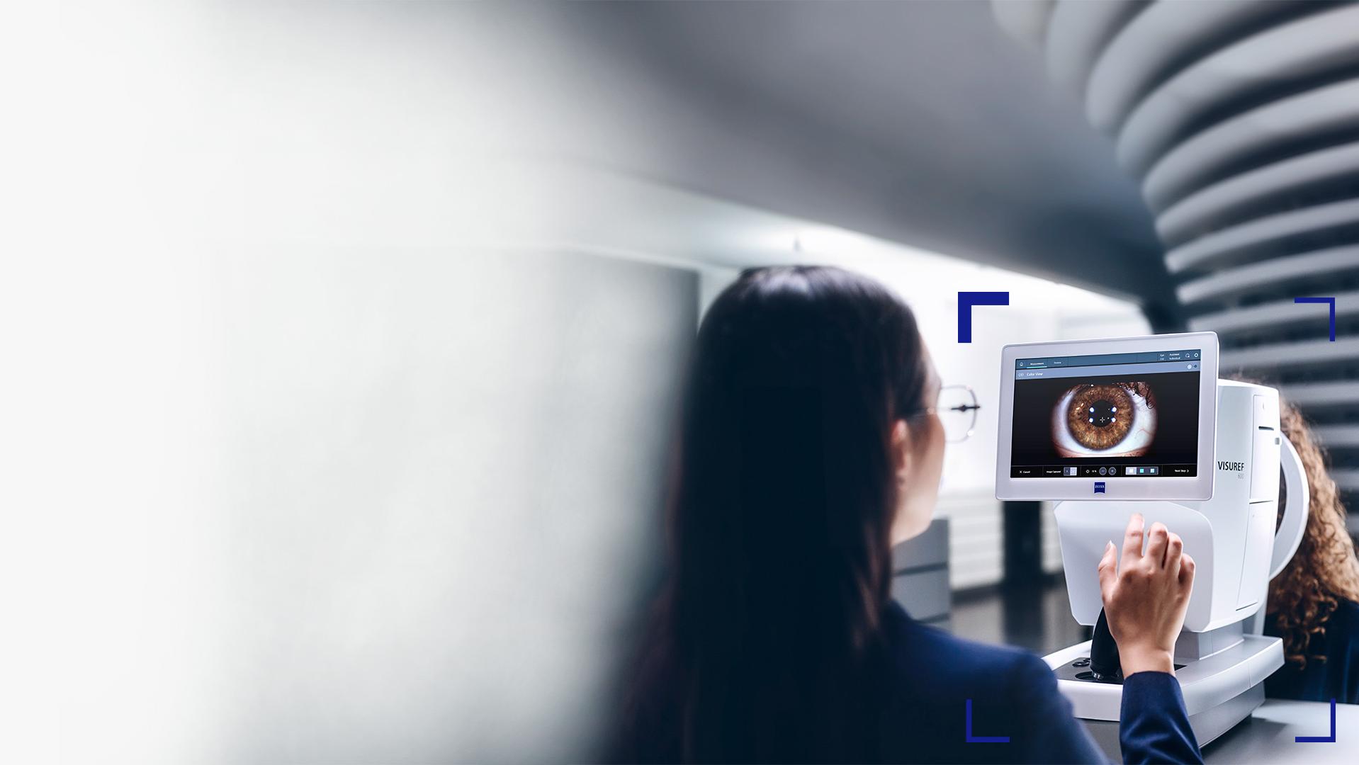 Une opticienne regarde l’écran du ZEISS VISUREF 600 qui affiche l’image d’un œil.