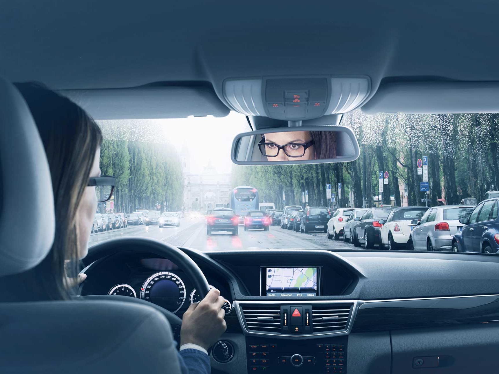 Een afbeelding van de binnenzijde van een auto met een vrouw op de bestuurdersstoel. 