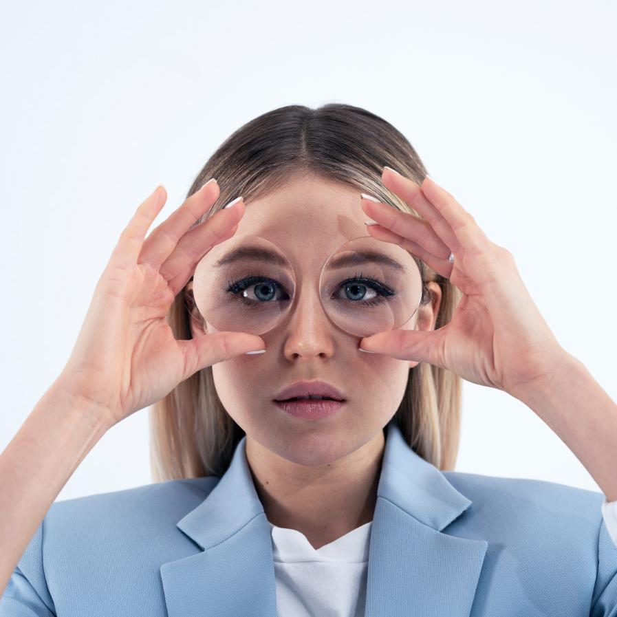 Een jonge vrouw houdt twee dikke glazen voor haar ogen om het vissenkomeffect te laten zien.