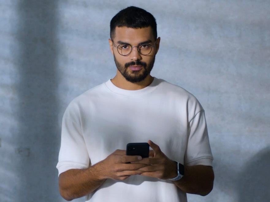 Un jeune homme portant des lunettes BlueGuard occupé avec son smartphone.
