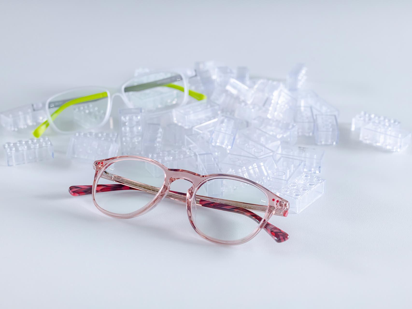 Twee kinderbrillen met ZEISS brillenglazen en DuraVision® kindercoatings. De glazen worden tussen doorzichtige kinderstenen geplaatst.