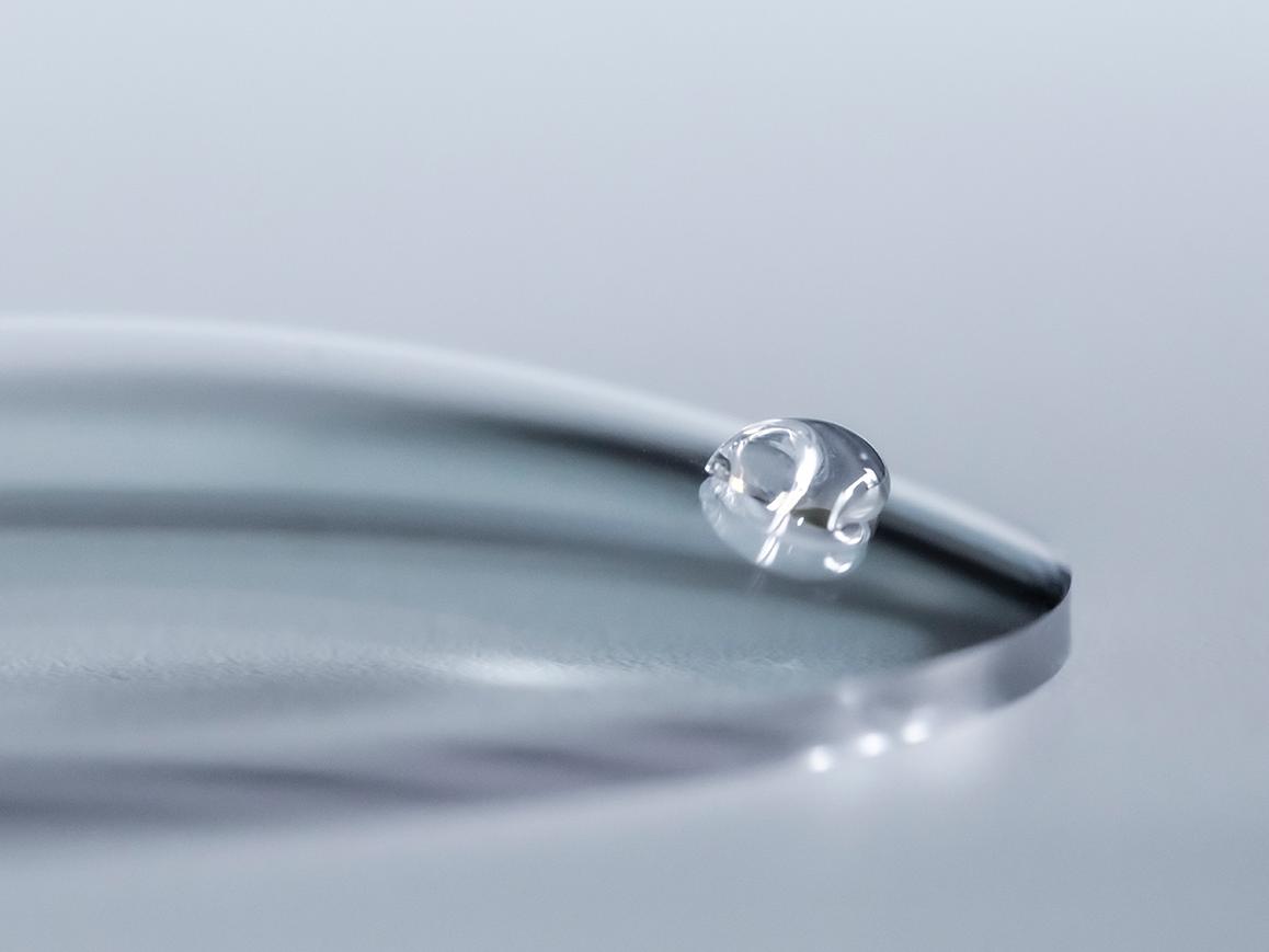 Een waterdruppel glijdt van een ZEISS brillenglas met een gemakkelijk te reinigen coating.
