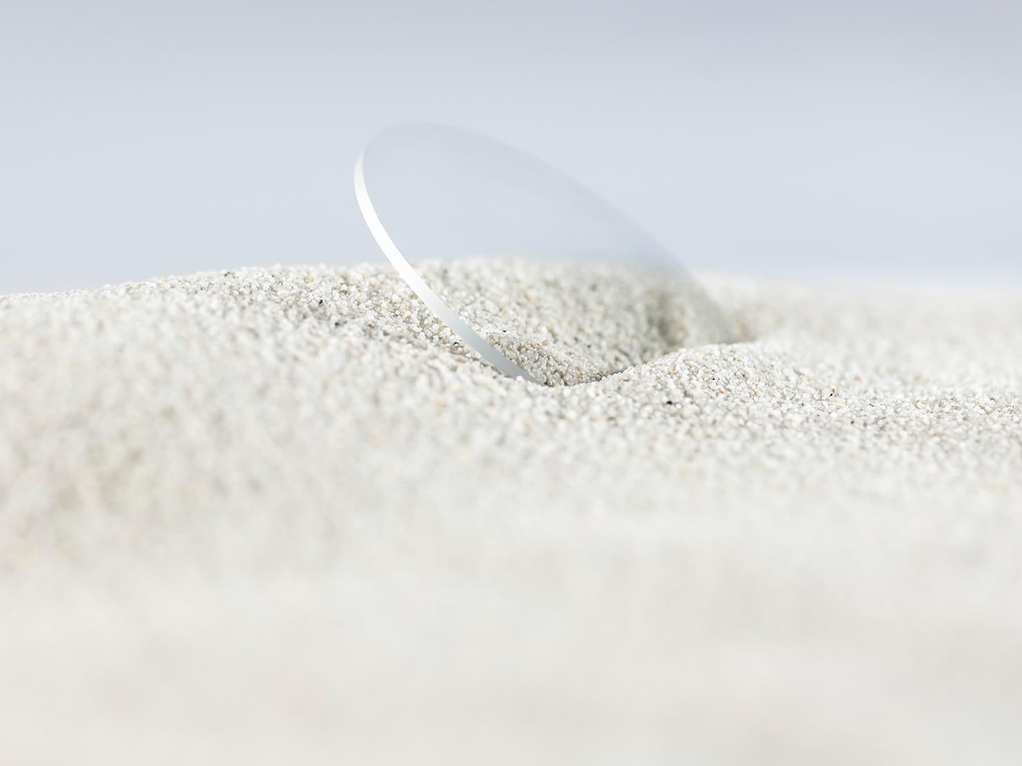 Een ZEISS brillenglas met een stevige coating is bedekt met ruw zand, maar blijft krasvrij.