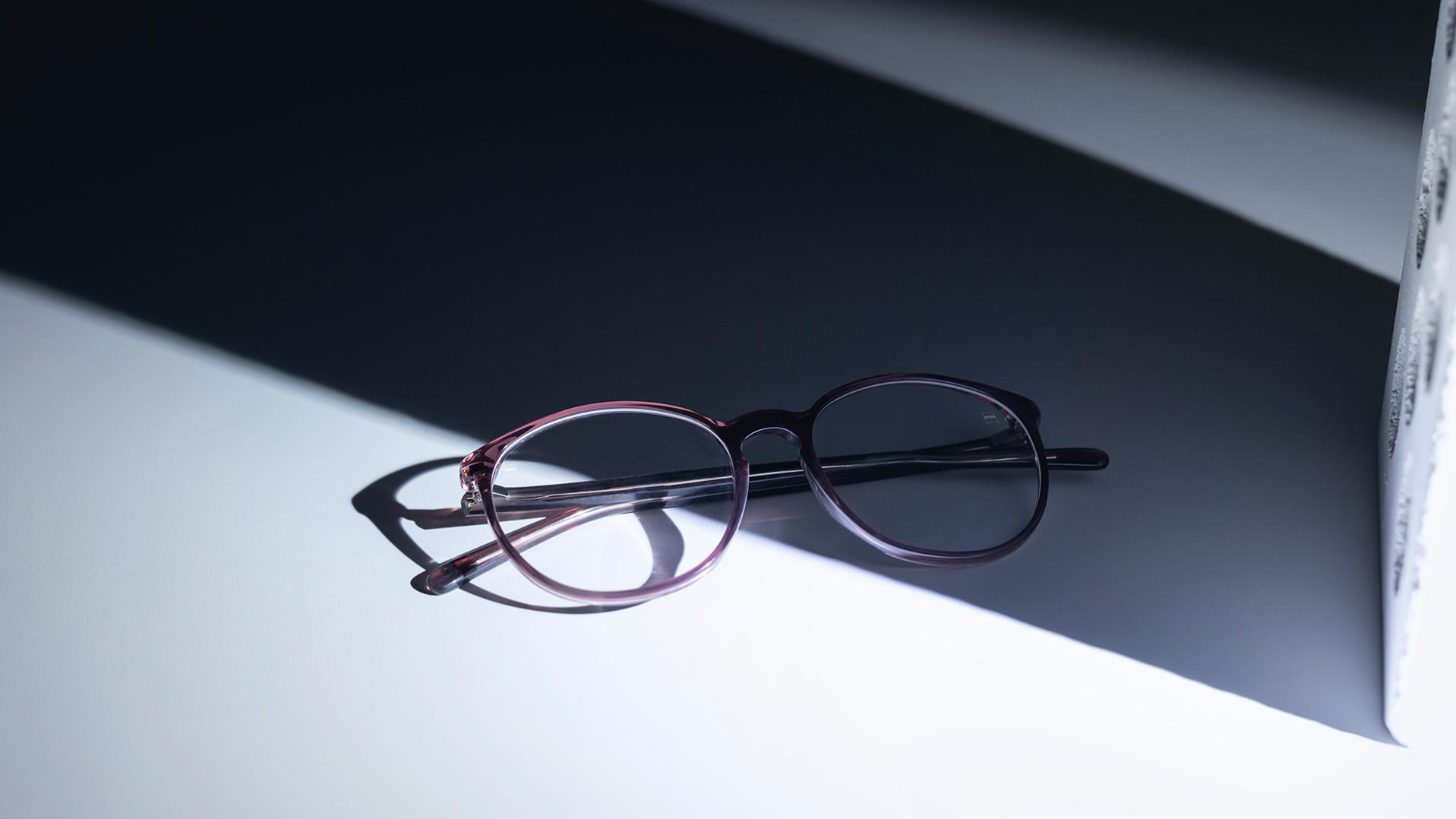 Een bril met ZEISS brillenglazen en DuraVision® coatings die half in de schaduw, half in de zon staat.