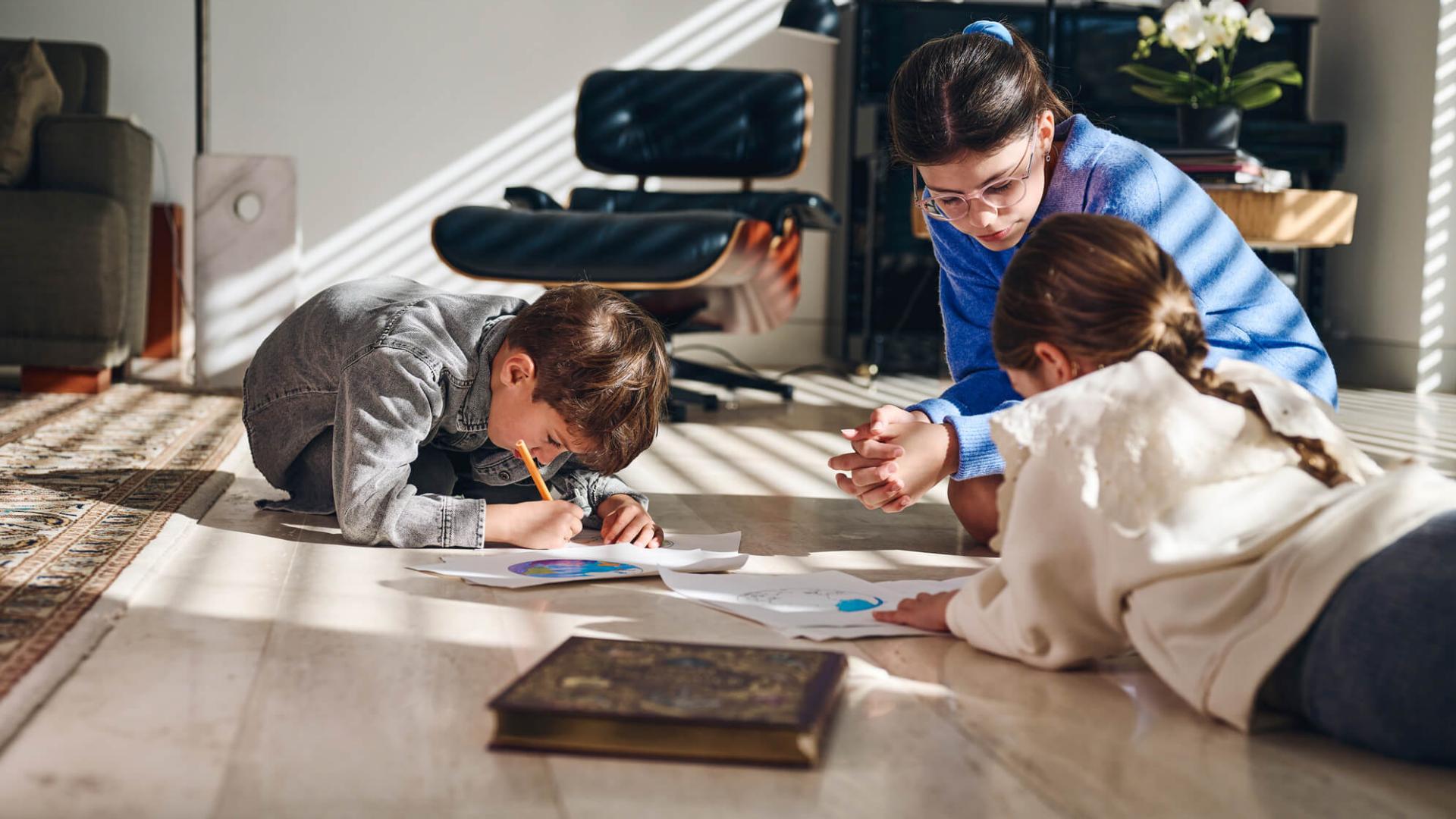 Kinderen tekenen op de grond en houden hun ogen dicht bij het papier. 