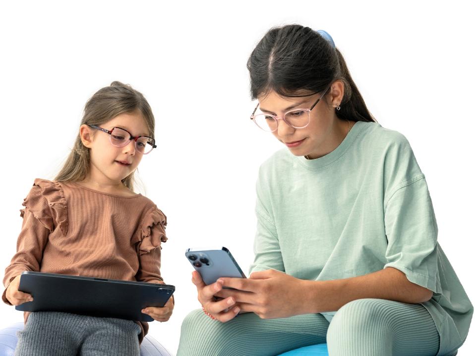 Twee meisjes kijken naar digitale apparaten op de voorgestelde afstand van meer dan 20 cm.