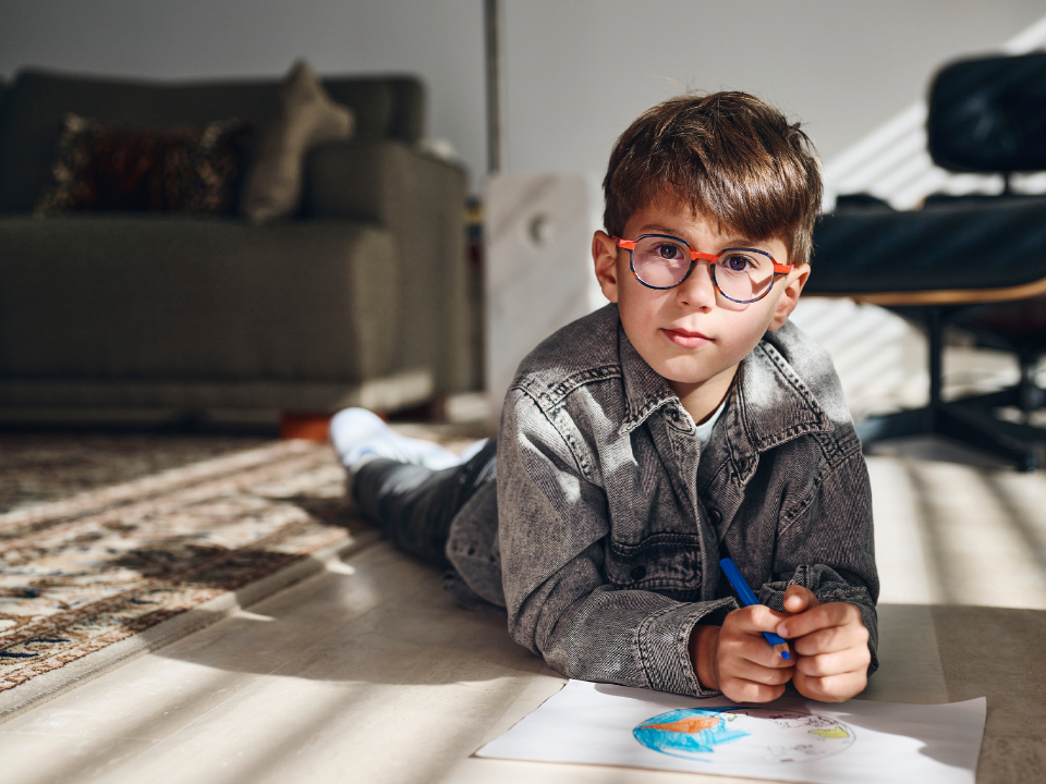 Een jongetje met ZEISS MyoCare brillenglazen kijkt recht in de camera.