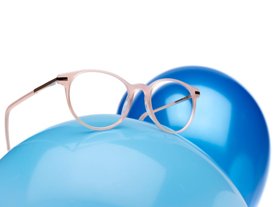 Roze brilmontuur met ZEISS MyoCare glazen op een blauwe ballon.