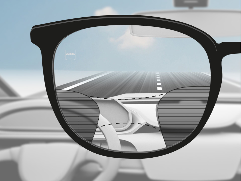 Een point of view-afbeelding van een bestuurder met ZEISS progressieve DriveSafe brillenglazen met helder zicht op de straat en het dashboard en wazige plekken links en rechts. 