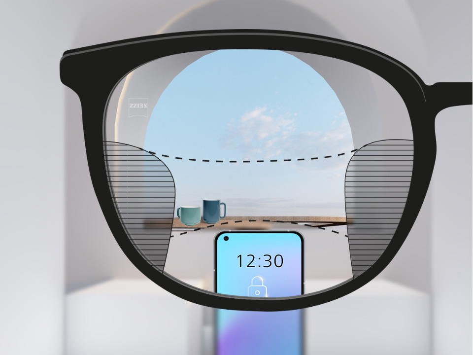 Een point of view-afbeelding met ZEISS progressieve SmartLife brillenglazen met een smartphone op de achtergrond, terwijl het objectief volledig helder is met links en rechts smalle wazige percelen.