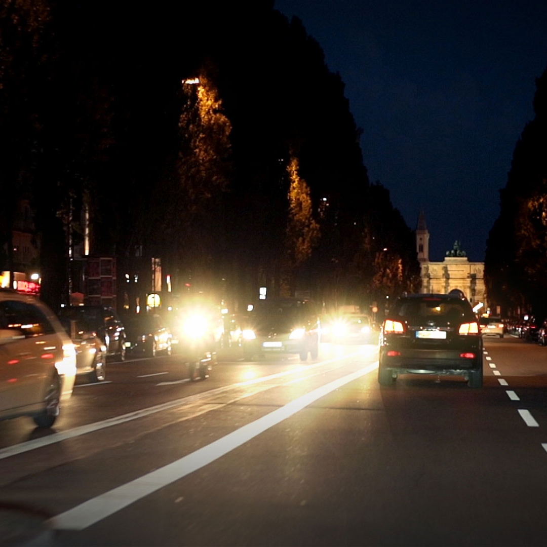 Verblindend licht van tegemoetkomend nachtelijk verkeer en schitteringen door natte wegen 