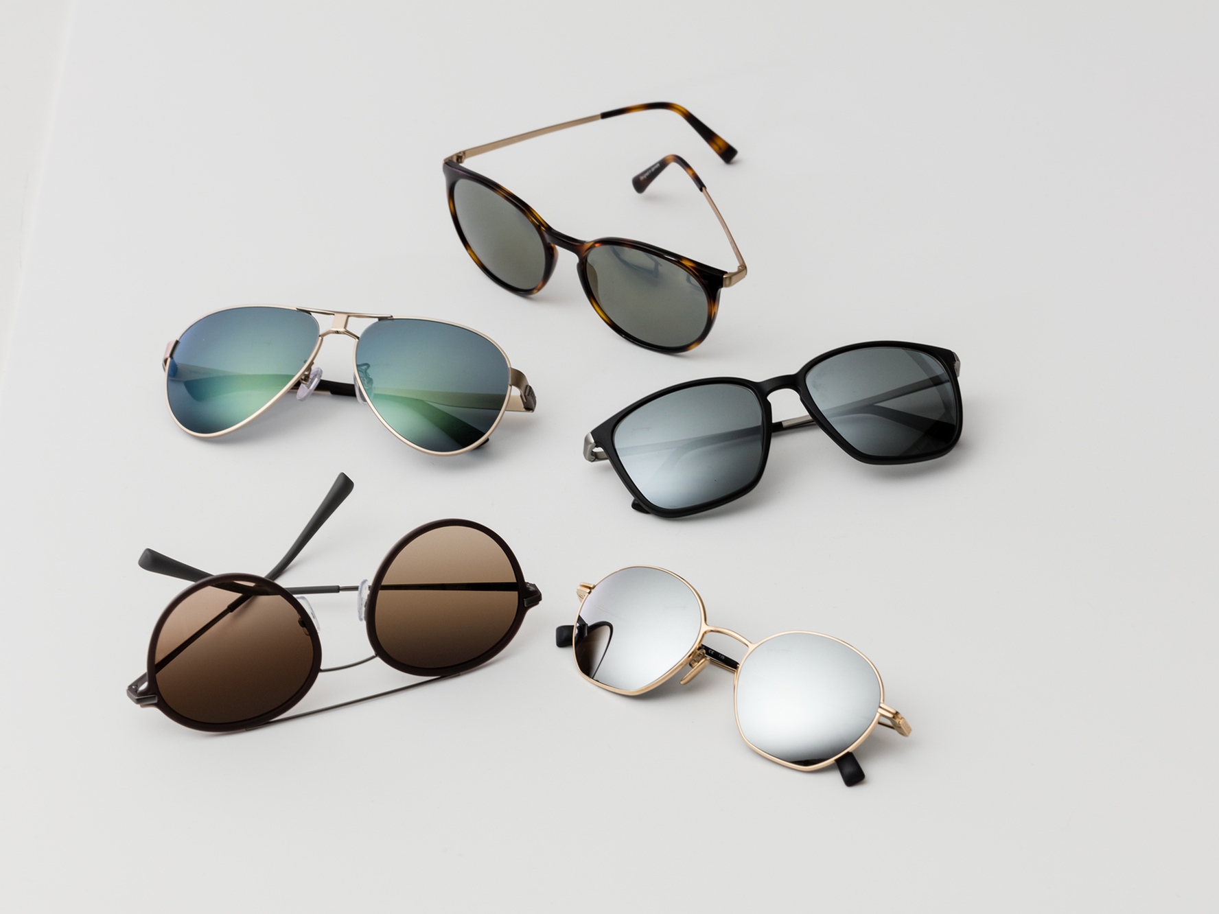 Vijf paar zonnebrillen met de klassieke zonwerende kleuren voor gemiddeld fel tot fel licht.