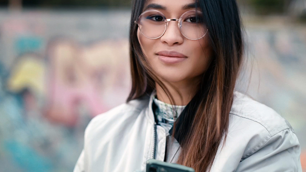 Een jonge vrouw in een skatepark die ZEISS unifocale SmartLife brillenglazen draagt.
